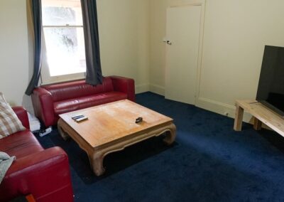 Cozy living room space with red leather sofas, a rustic wooden coffee table, and a large TV setup, providing a comfortable relaxation area for guests in Cabins, Dwellings, Caravans, & Glamping Tents. The inviting decor and ample seating make this a perfect spot for unwinding after a day of exploration